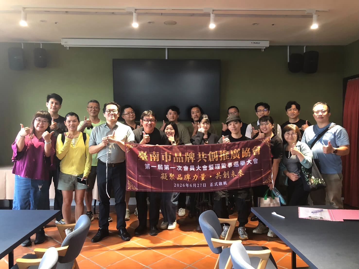 臺南市品牌共創推廣協會成立大會合影,與會夥伴共同手持第一屆第一次會員大會暨理監事選舉大會布條